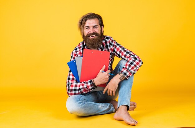 Homem barbudo brutal usa camisa quadriculada com barba exuberante e bigode segurando pasta com documentos em papel