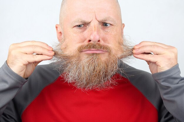 Homem barbudo careca tocando a barba