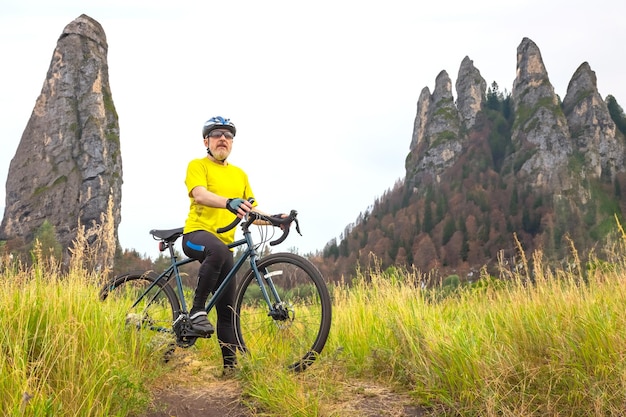 homem barbudo ciclista em roupas amarelas está descansando em uma bicicleta na estrada em esportes de natureza