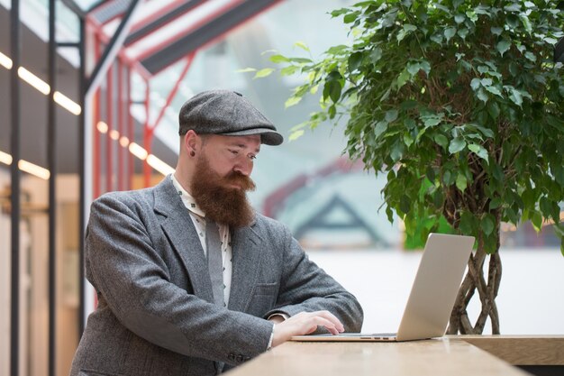 Homem barbudo com blazer de lã trabalhando em um laptop