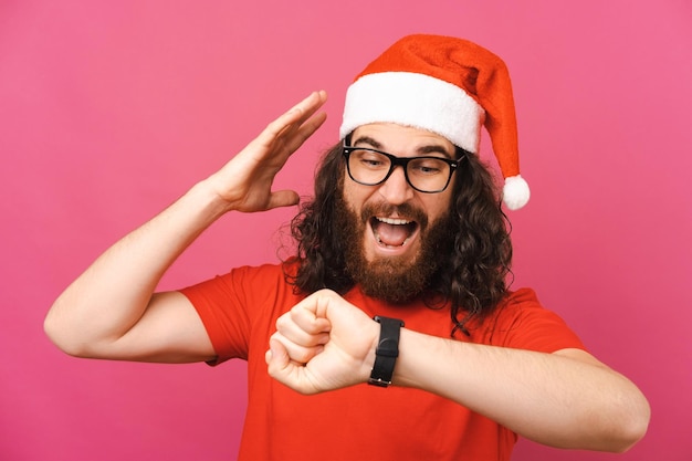 Homem barbudo com chapéu de Natal está atrasado e assiste seu relógio de pulso