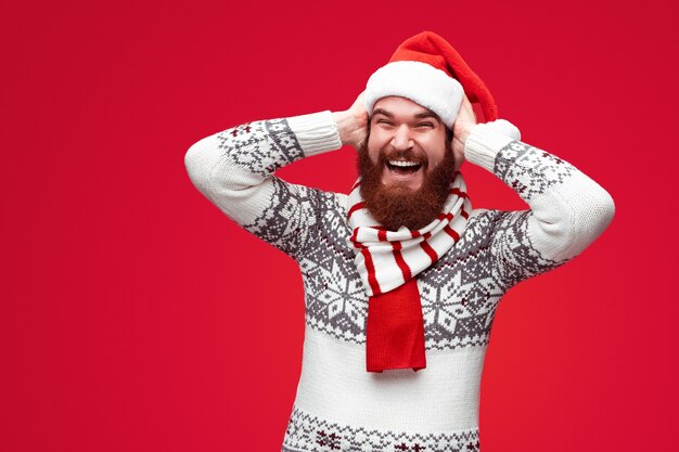 homem barbudo com chapéu de Natal rindo e se chocando