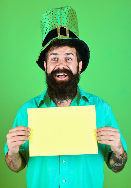 Homem barbudo com chapéu verde segura placa amarela. homem barbudo com chapéus verdes comemora o dia de patrick. homem vestido com chapéu de carnaval saint patricks. dia de são patrick. irlanda tradicional.