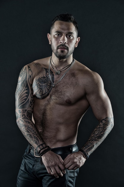 Homem barbudo com corpo tatuado Homem com torso nu sexy em jeans Modelo de tatuagem com tanquinho e ab Atleta ou esportista com peito e barriga musculosos Filtro vintage de esporte ou fitness e cuidados com o corpo