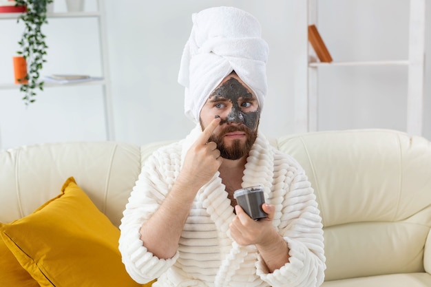 Homem barbudo com pele limpa e fresca, usa máscara de argila de beleza no rosto e gosta de tratamentos de beleza no spa