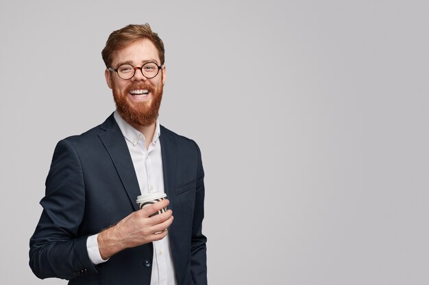 homem barbudo com um copo de bebida quente fresca sorrindo