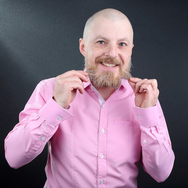 Homem barbudo com uma camisa rosa tocando a barba