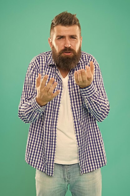 Homem barbudo confuso alcoólatra em camisa xadrez casual cara caucasiano com barba e bigode em fundo azul hipster masculino maduro tendo uma conversa constrangimento
