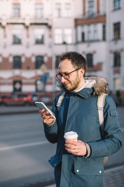 Foto homem barbudo de azul conversa no telefone e gosta de café hipster vibra calor e alegria