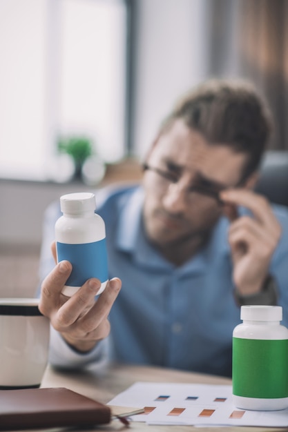 Foto homem barbudo de camisa azul lendo sobre vitaminas