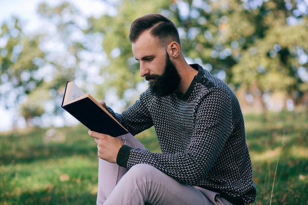 Foto homem barbudo de estudante hipster lendo um livro ao ar livre