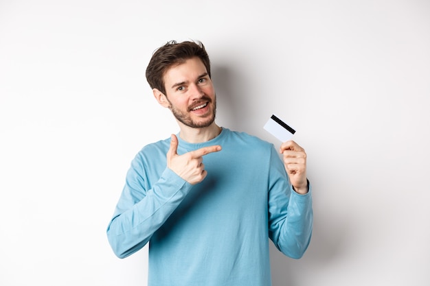 Homem barbudo e bonito recomendando cartão de crédito do banco, sobre fundo branco