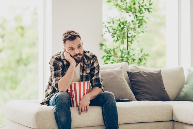 Homem barbudo e cansado com camisa xadrez e jeans jeans entediado