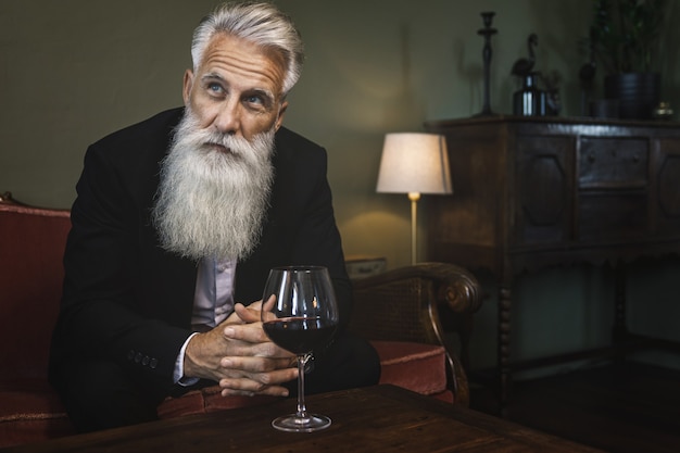 Homem barbudo elegante e bonito bebendo vinho tinto