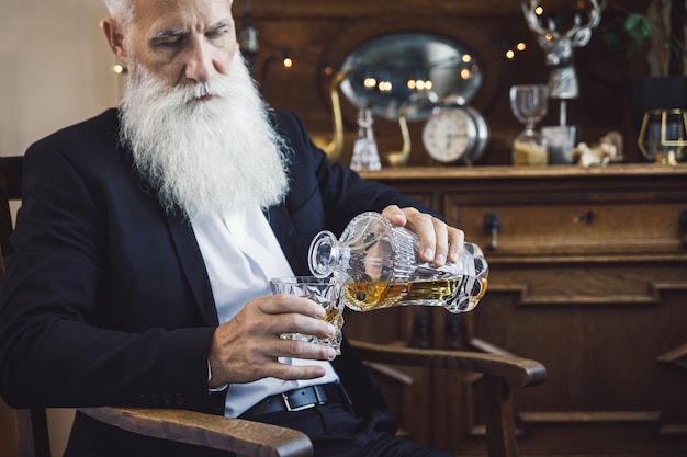 Homem barbudo elegante e bonito com um copo de uísque