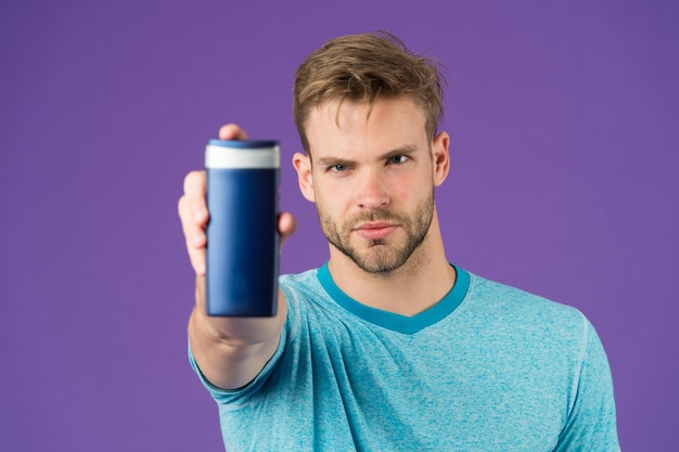 Homem barbudo elegante segura garrafa de plástico Homem bonito se preocupa com a aparência usa produto cosmético ou higiênico Homem mostra seu xampu ou condicionador favorito para cabelo Garrafa de xampu melhor escolha