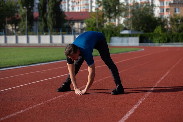 Homem barbudo em forma se aquece antes do treino no estádio. Espaço para texto