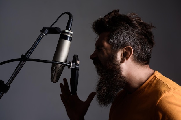 Homem barbudo emocional gritando no microfone música show business estúdio de gravação cantor masculino com