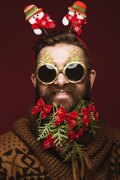 Foto homem barbudo engraçado em uma imagem de ano novo como papai noel com enfeites em sua barba. festa de natal.