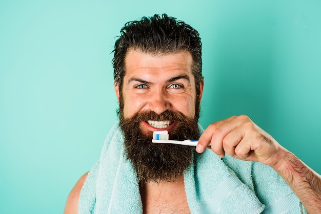 Homem barbudo escovando os dentes com escova e pasta de dentes. higiene dental. tratamentos matinais.