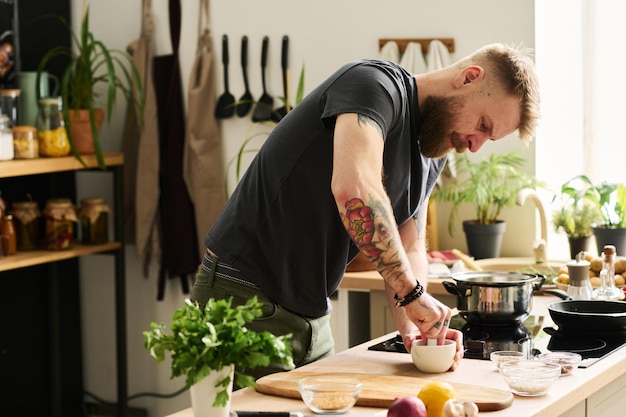 Homem barbudo esmagando especiarias na cozinha