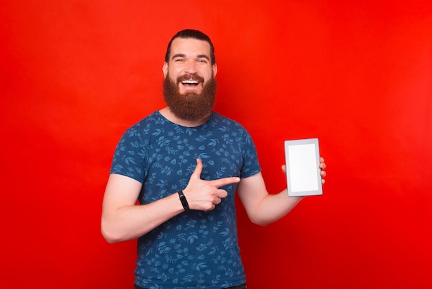 Homem barbudo está apontando para a tela de um tablet.