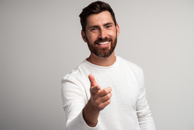 Homem barbudo extremamente feliz rindo e apontando o dedo para você olhando para a câmera, piada engraçada e ridícula. Foto de estúdio interna isolada no fundo branco