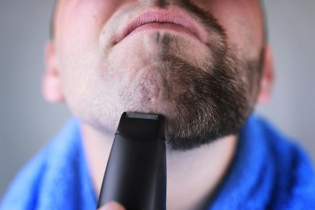 homem barbudo fazendo a barba elétrica