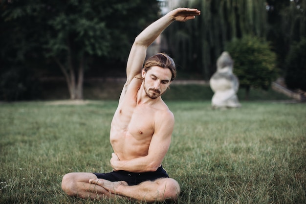 Homem barbudo fazendo yoga no parque verde