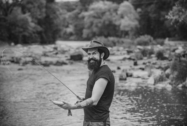 Homem barbudo hipster pegando truta pescador pegou um homem peixe pescando no rio