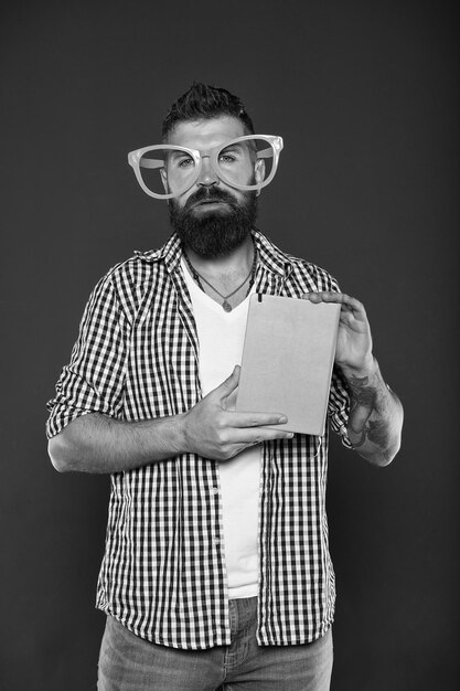 Homem barbudo hipster usa óculos engraçados segure o bloco de notas ou livro Ilumine seu dia Leia este livro Sentido de quadrinhos e humor História engraçada O estudo é divertido Livro engraçado para relaxar Espaço para cópia da capa do livro