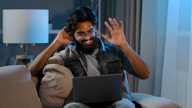 Homem barbudo indiano árabe millennial empresário freelancer sentado em casa sofá à noite