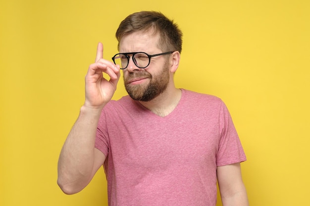 Homem barbudo insidioso de óculos e uma camiseta rosa teve a ideia de que ele levantou o dedo e olhou maliciosamente