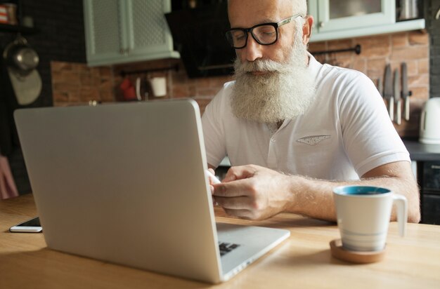 Homem barbudo maduro com laptop e óculos