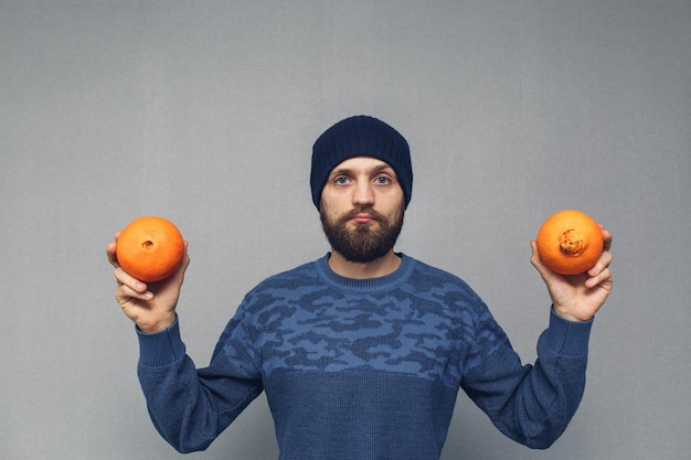 Homem barbudo mostra conceito de laranjas normais e feias de hemorróidas ou doenças proctológicas