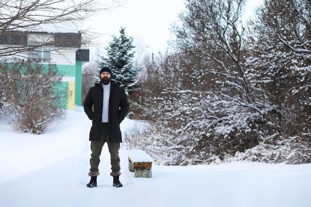 Homem barbudo na floresta de inverno. Atraente jovem feliz com barba caminhada no parque.