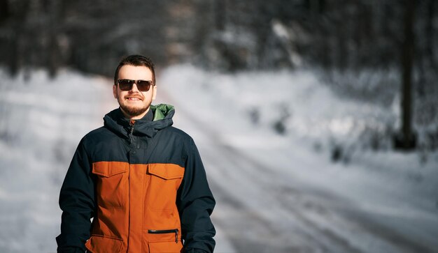 Homem barbudo na floresta de inverno Guy usando óculos escuros durante o tempo nevado