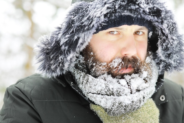 Homem barbudo na floresta de inverno. Jovem feliz atraente com barba andar no parque.