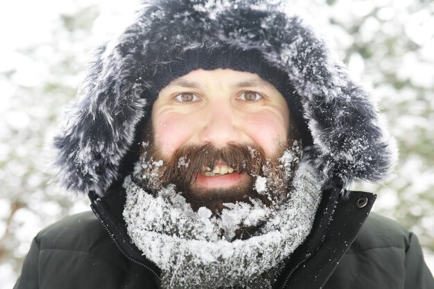 Homem barbudo na floresta de inverno. Jovem feliz atraente com barba andar no parque.