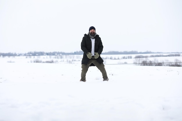 Homem barbudo na floresta de inverno. Jovem feliz atraente com barba andar no parque.