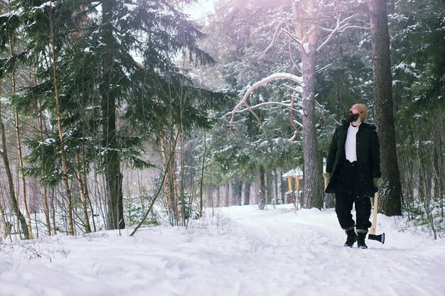 Homem barbudo na floresta de inverno. Jovem feliz atraente com barba andar no parque.