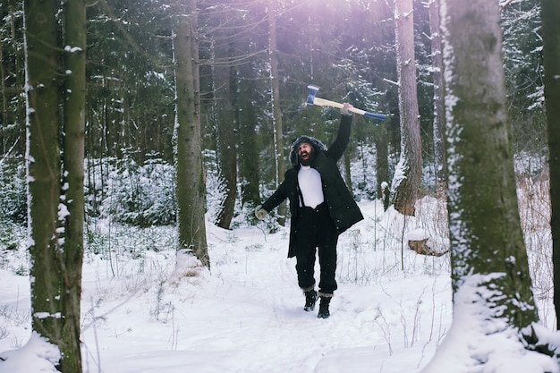 Homem barbudo na floresta de inverno. Jovem feliz atraente com barba andar no parque.