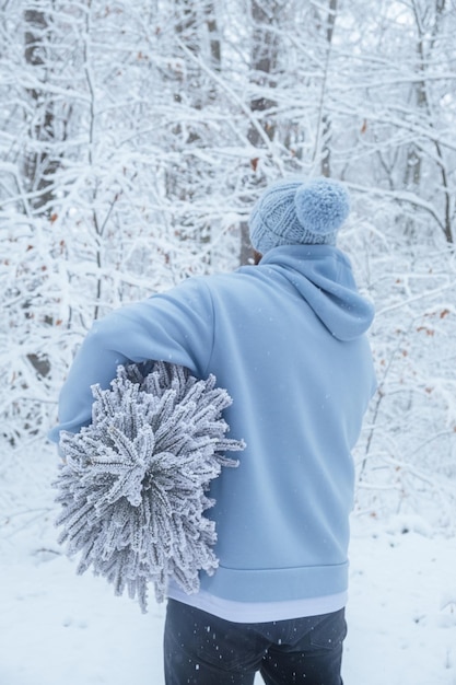 Homem barbudo no boné segurando a vista traseira da árvore de Natal