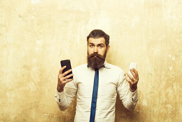 Homem barbudo ou hipster compara celular e smartphone