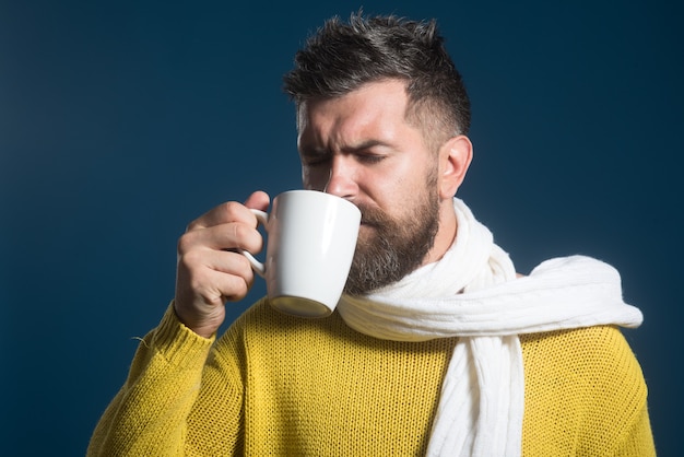 Homem barbudo se aquecendo com chá quente no inverno. homem bebe bebida quente. tempo frio. bebidas quentes.