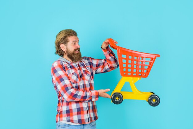 Homem barbudo segurando um carrinho de compras vazio com desconto na promoção de compras de supermercado