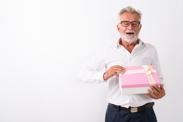 homem barbudo sênior feliz sorrindo ao abrir a caixa de presente com os olhos fechados no branco