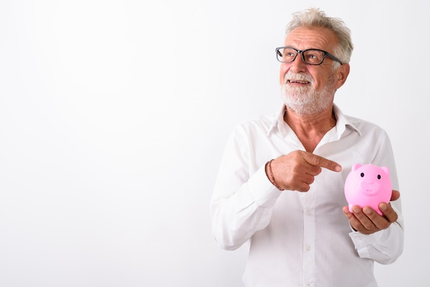 Foto homem barbudo sênior feliz sorrindo e pensando enquanto aponta para o cofrinho com óculos em branco