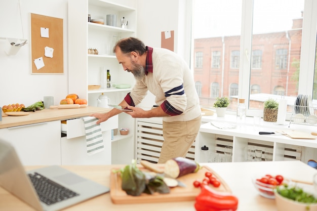 Homem barbudo sênior na cozinha