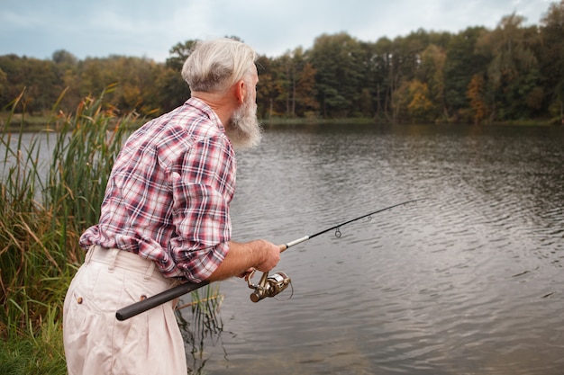 Homem barbudo sênior pescando em um lago